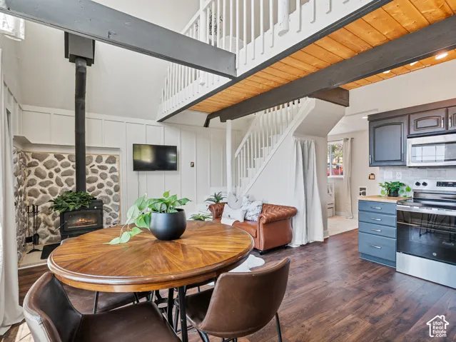 Open-concept living area featuring, new flooring, a stone-faced wood-burning stove, and a white paneled accent wall
