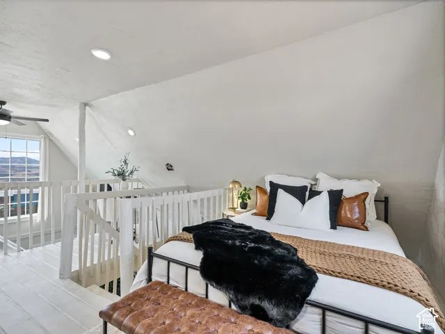 Loft bedroom featuring vaulted ceiling, recessed lighting, and a window overlooking distant scenery