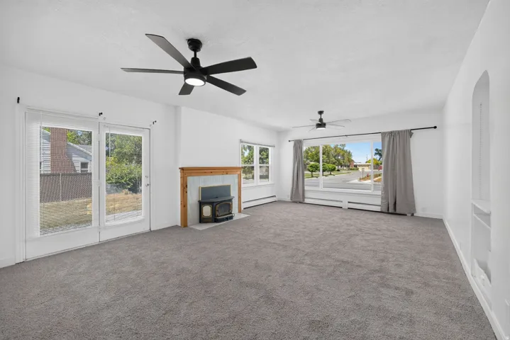 Spacious room featuring neutral carpeting, a wood-surround fireplace with a hearth, and a built-in wall niche