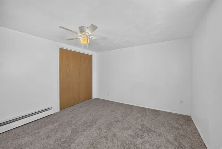 Room featuring light gray carpet flooring, white painted walls, and a ceiling fan with integrated lighting