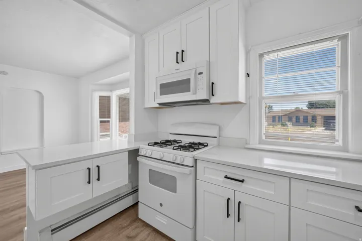 Bright kitchen featuring white shaker cabinetry, white countertops, a gas range, and an over-the-range microwave