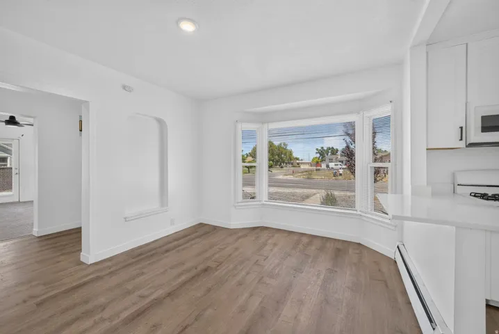 Bright dining area featuring a prominent bay window, recessed ceiling lighting, wood-finish flooring, a built-in wall niche, and white cabinetry with a matching countertop