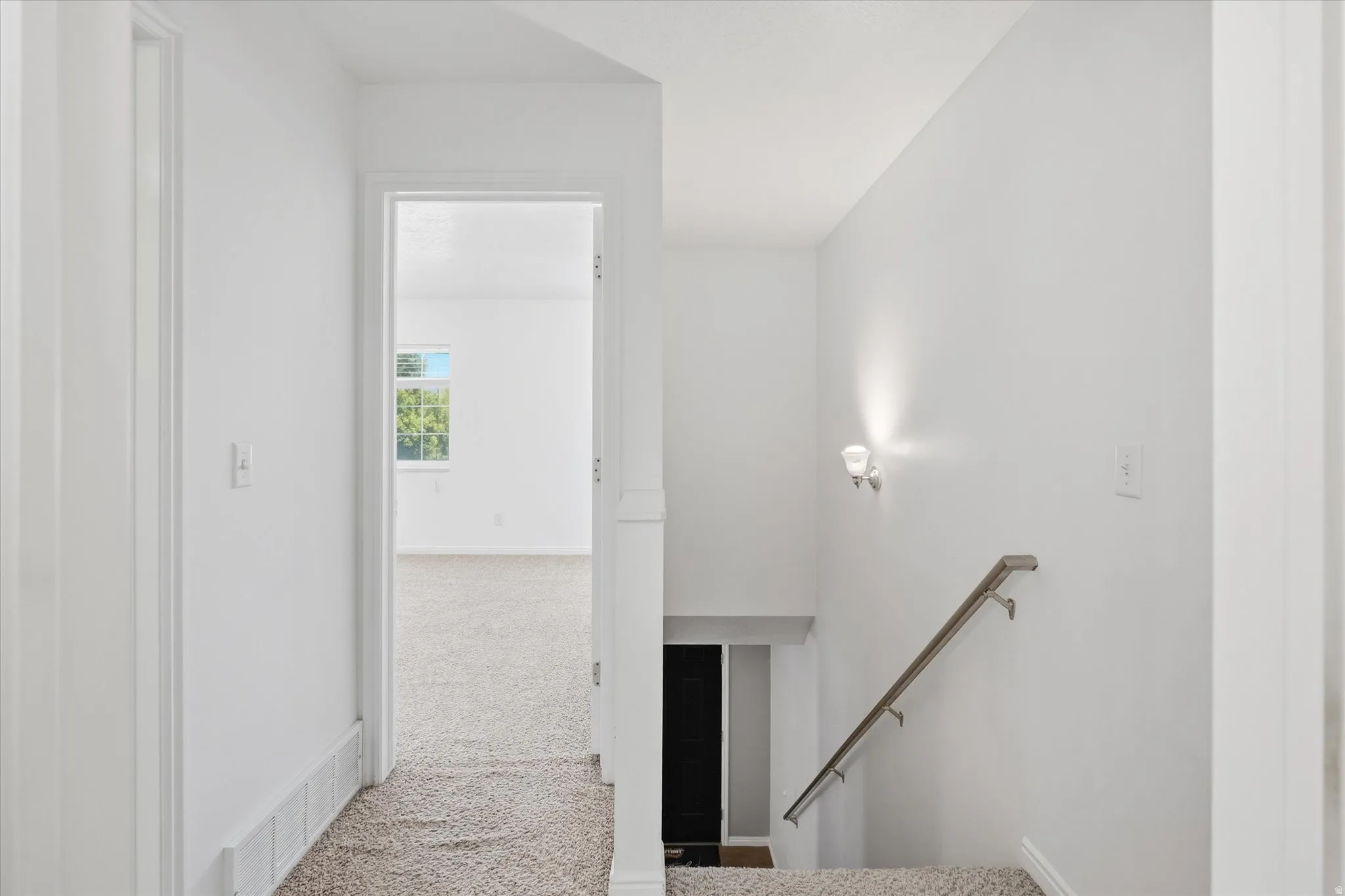 Hallway with light gray carpeting and white walls