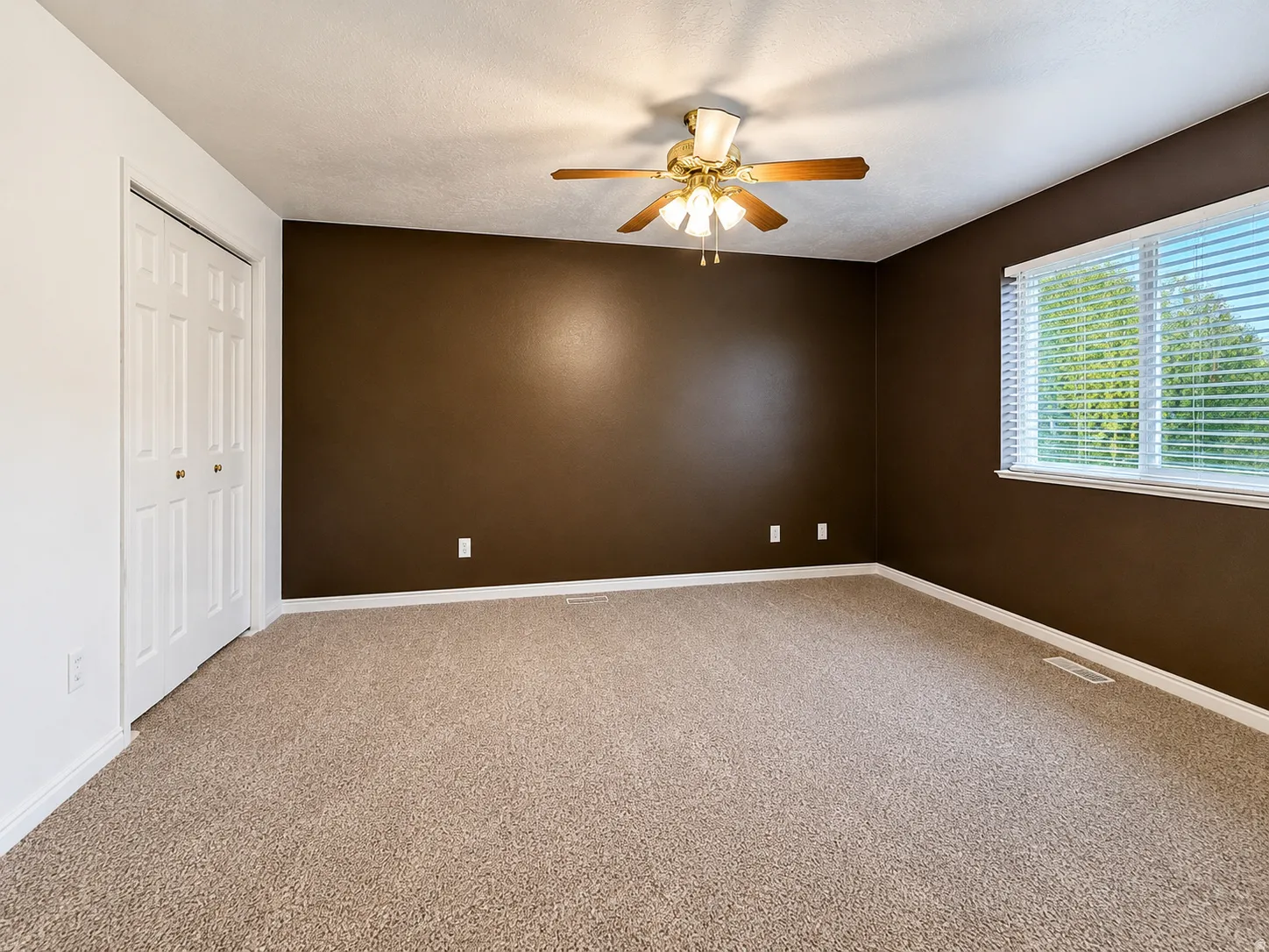 Wall-to-wall carpeting, window with horizontal blinds, ceiling fan with integrated lighting, and bi-fold closet doors