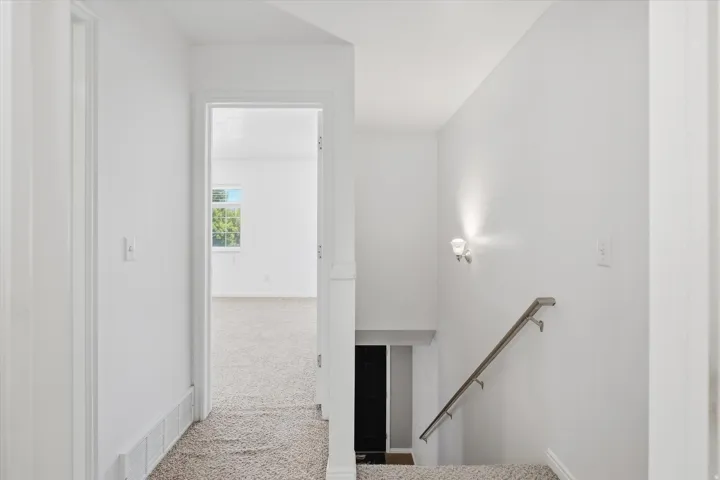 Hallway with light gray carpeting and white walls
