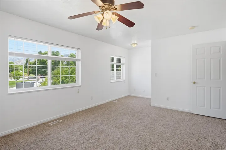 Spacious room featuring neutral carpet flooring, white walls, and a multi-pane window with white blinds