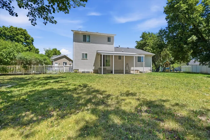 Spacious backyard featuring a covered patio, extensive lawn, and mature perimeter trees