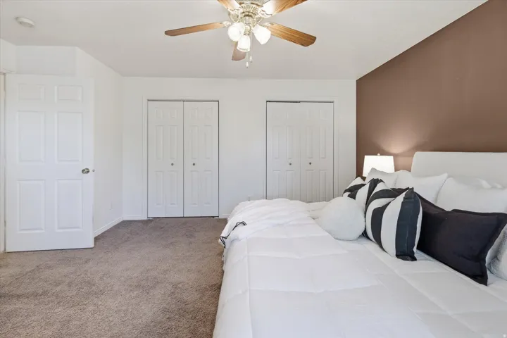 Bedroom featuring plush carpeting and a ceiling fan with integrated lighting