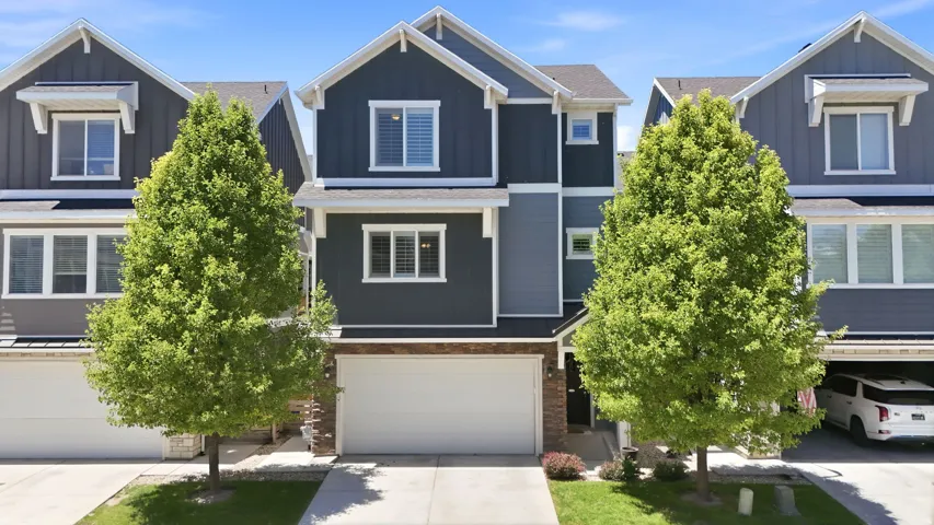 Modern townhouse facade featuring multi-toned siding, white trim accents, a single-car garage, and a covered entry