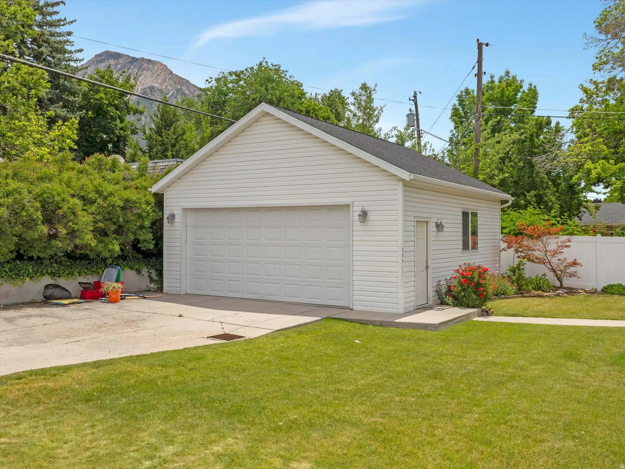 Detached two-car garage with white siding, black shingle roof, and a side access door