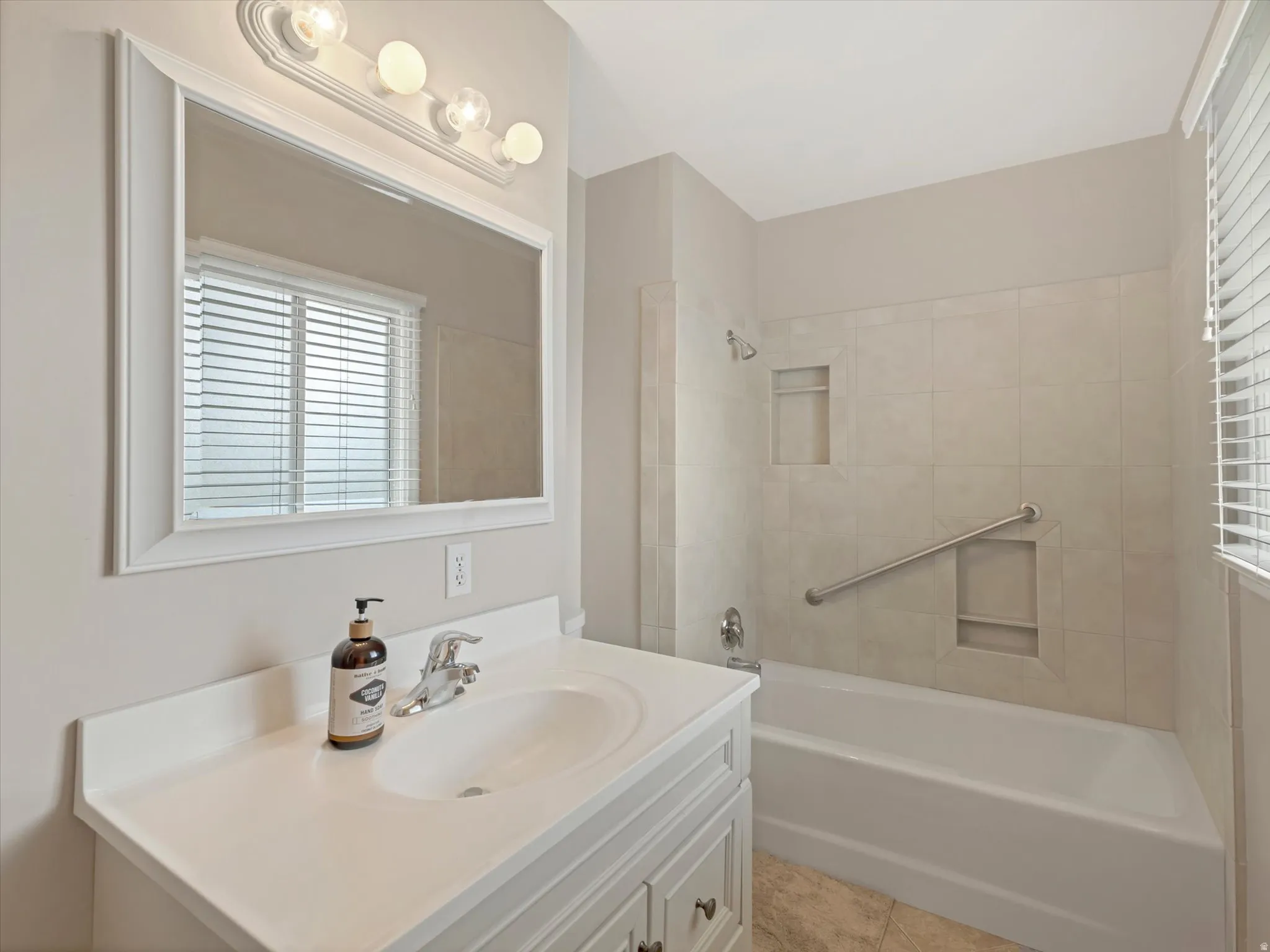 Bathroom featuring a white vanity with integrated sink, chrome faucet, and a large framed mirror with a four-light fixture