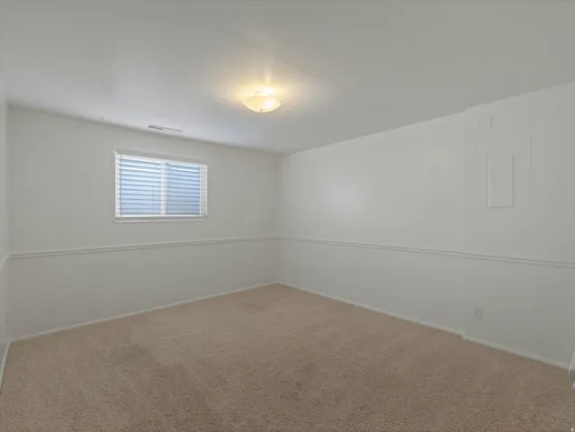Neutral-toned carpeting paired with white walls and wainscoting
