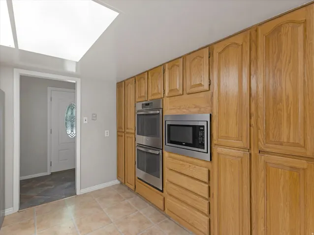 Kitchen featuring extensive wood cabinetry, built-in double ovens, and an integrated microwave