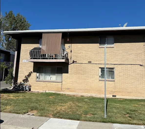 Two-story brick exterior building featuring an upper-level balcony with metal railing