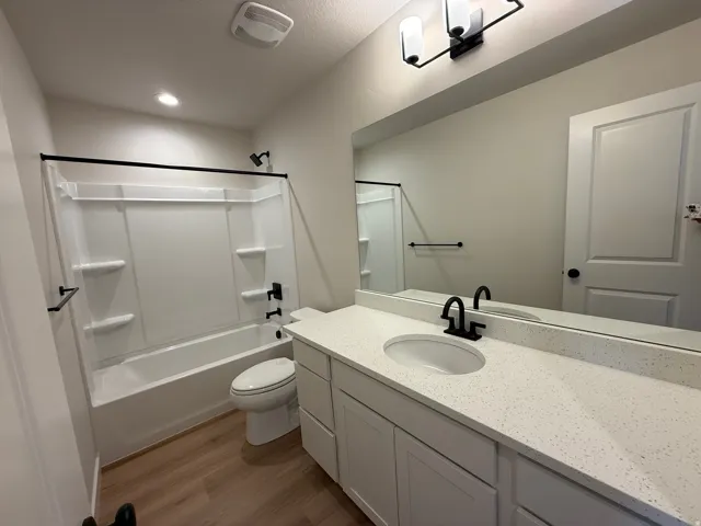 Bathroom featuring a white vanity with an undermount sink, speckled countertop, and matte black fixtures