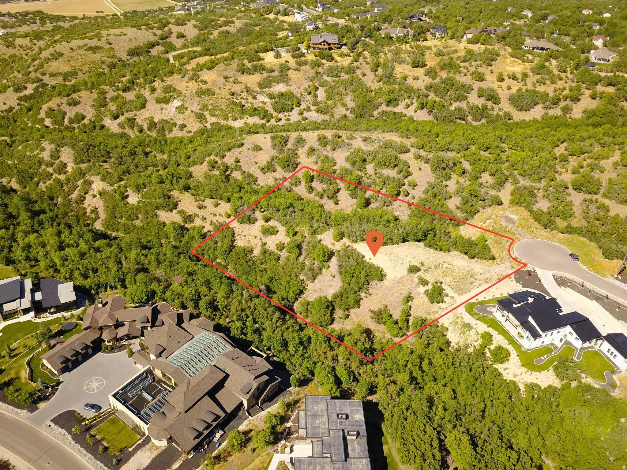 Expansive undeveloped lot featuring natural vegetation and a partial paved road boundary