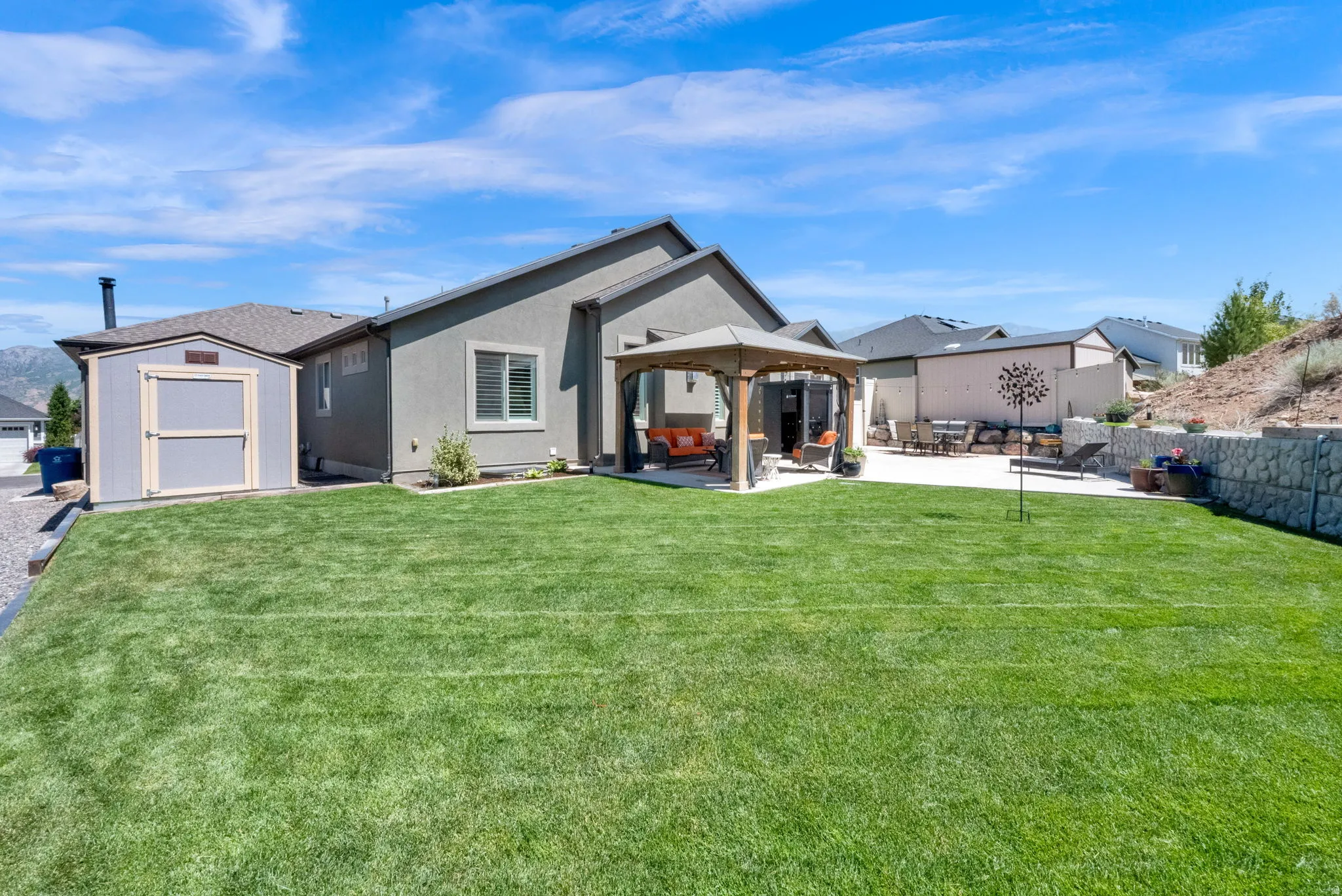 Expansive rear yard featuring a large turf area, a concrete patio, and a dedicated storage shed