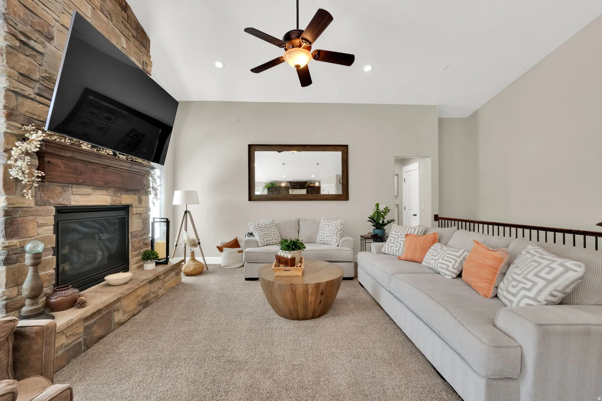 Living area featuring a floor-to-ceiling stone fireplace with a wood mantel, vaulted ceiling, recessed lighting, and a dark wood-finish ceiling fan