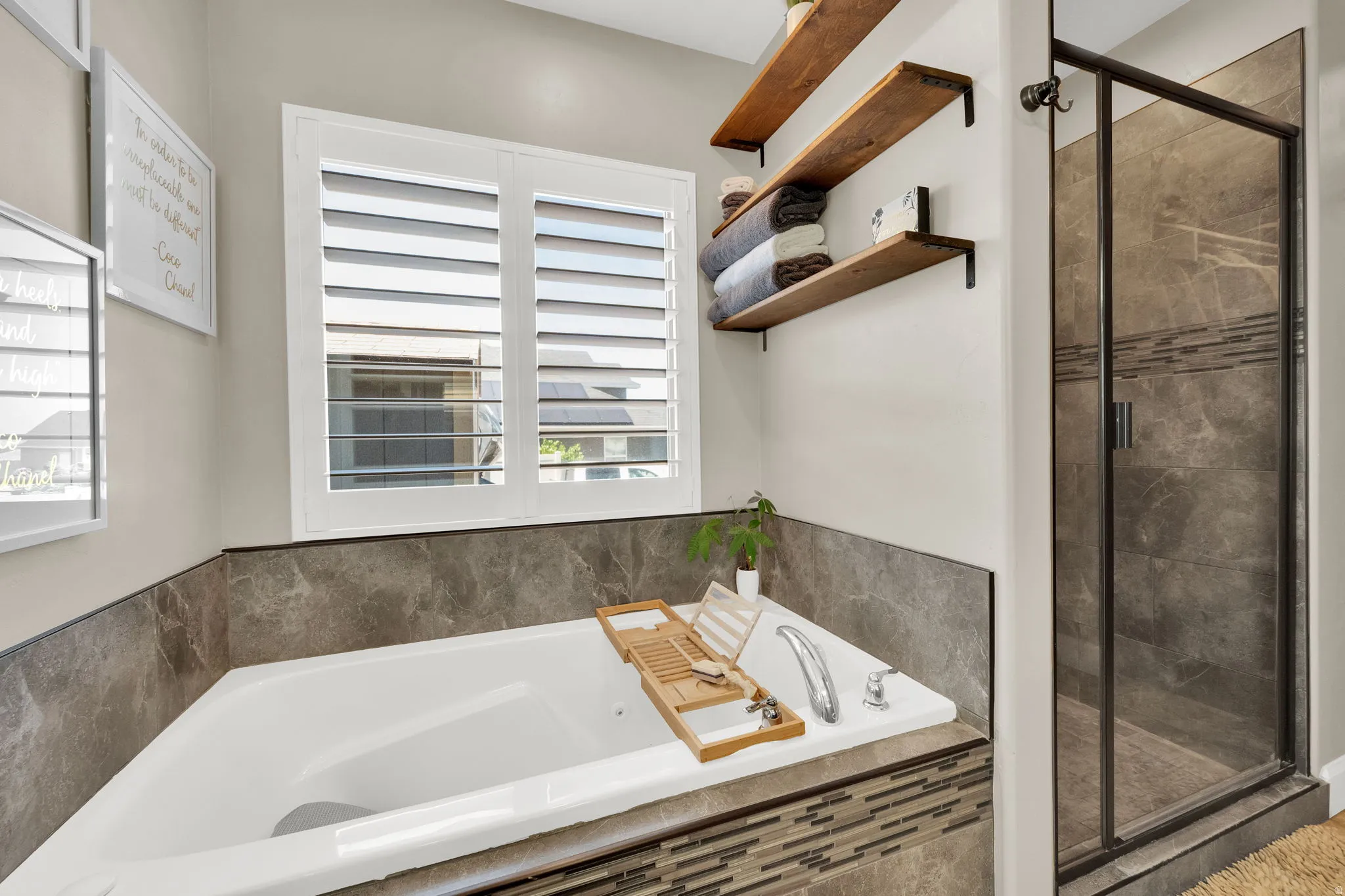 Deep soaking tub with integrated fixtures, full tile surround, and decorative mosaic accent band