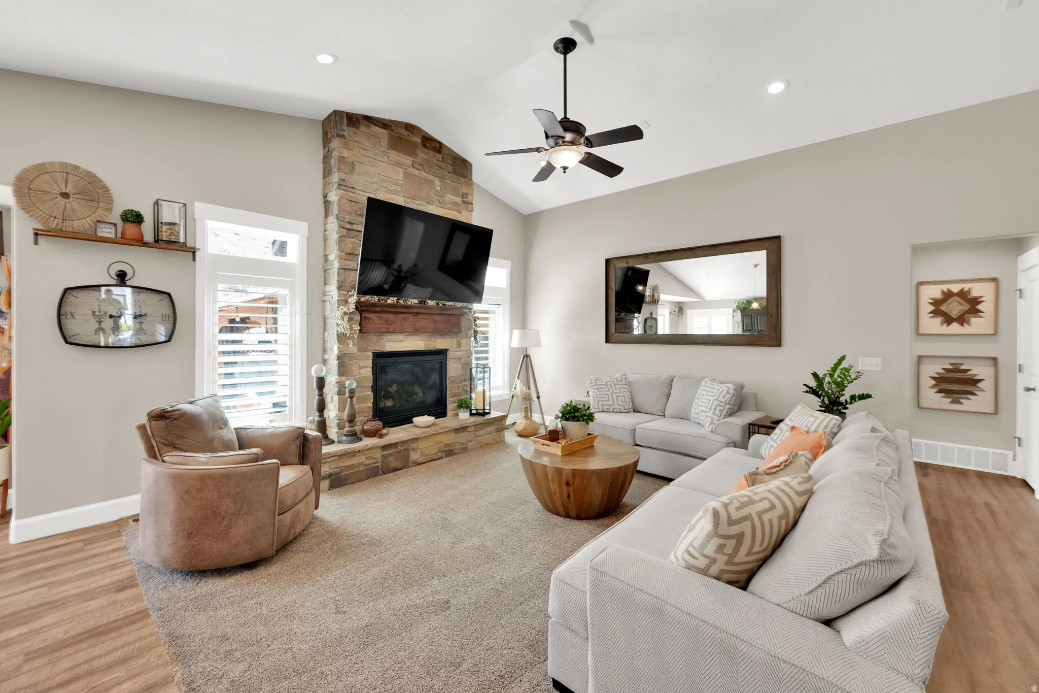 Living area featuring a floor-to-ceiling stone fireplace with a wood mantel, vaulted ceiling, and recessed lighting