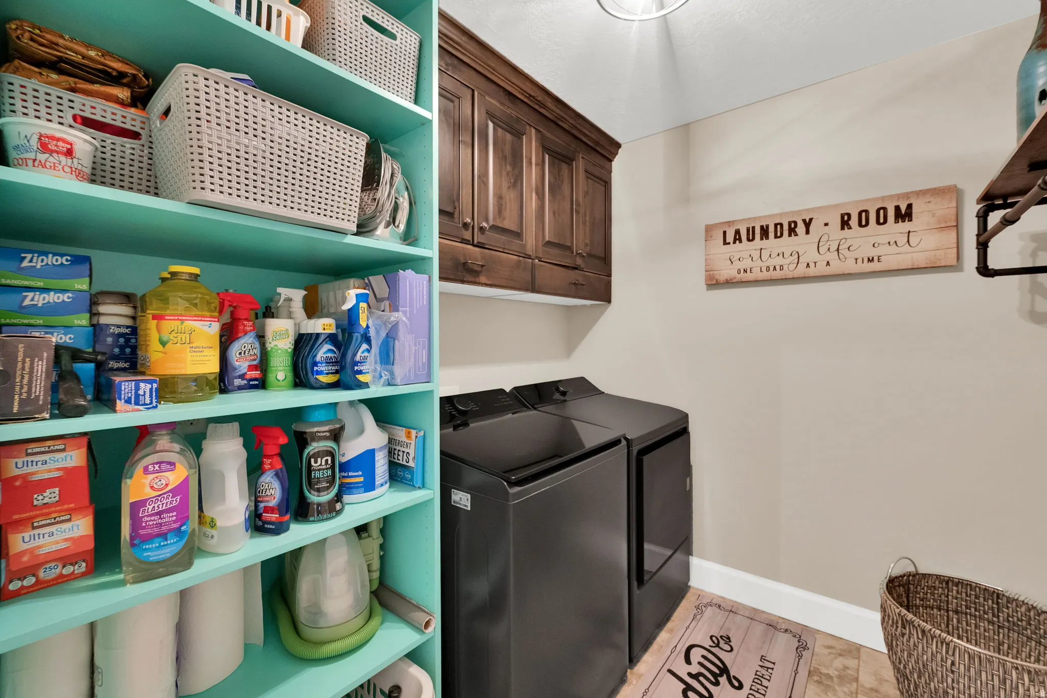 Dedicated laundry space featuring teal shelving, dark wood cabinetry, and a light-toned flooring