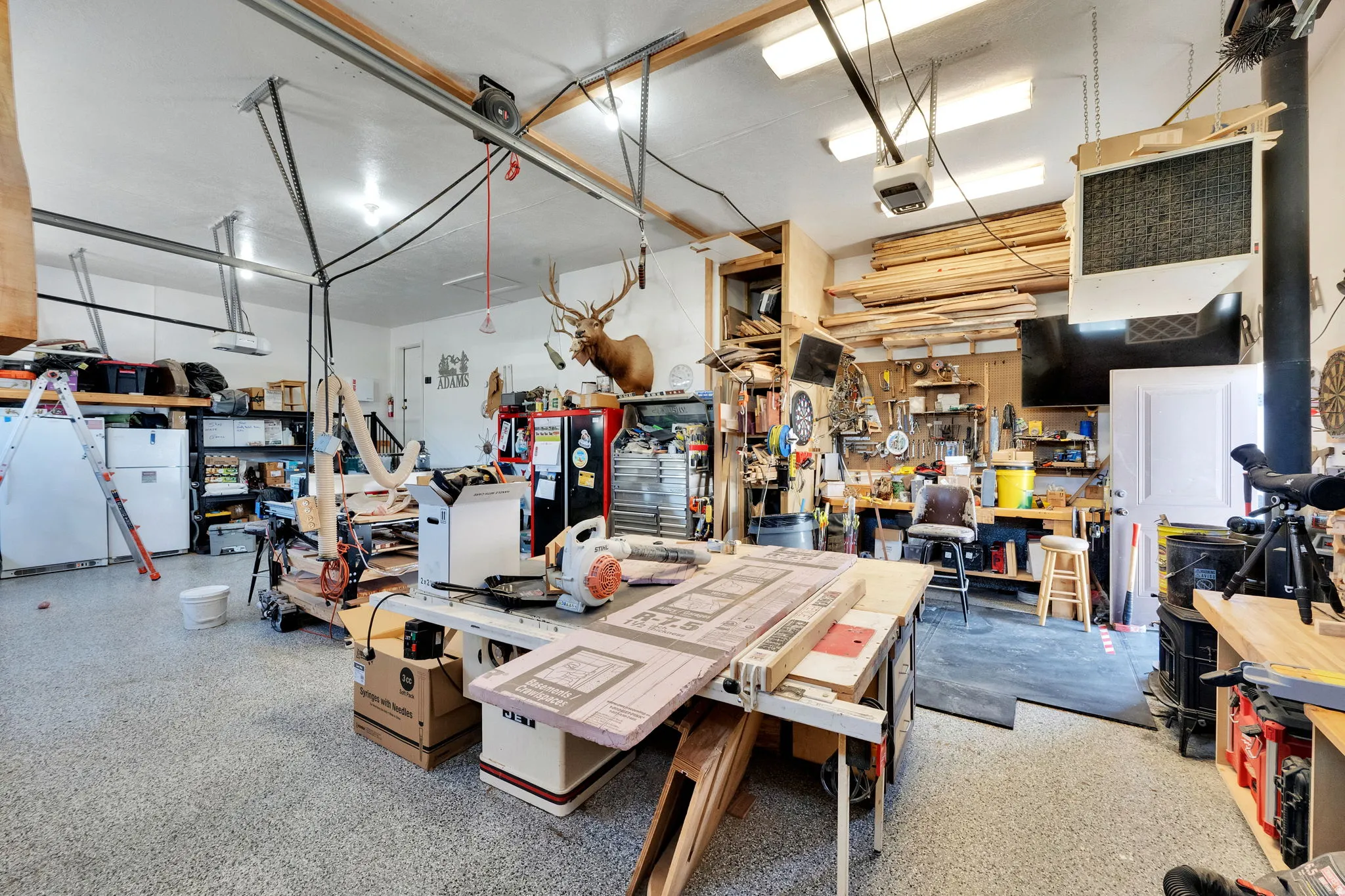 Expansive garage space featuring a speckled epoxy floor and ample overhead fluorescent lighting