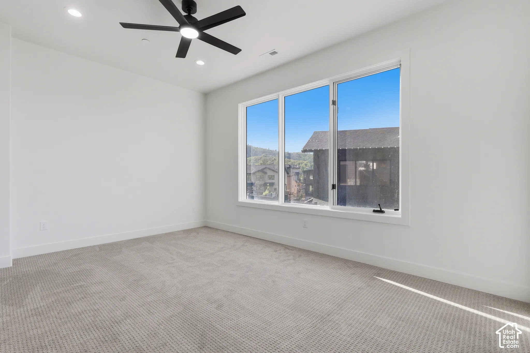 Bright room featuring a large window with multiple panes, recessed lighting, and a ceiling fan