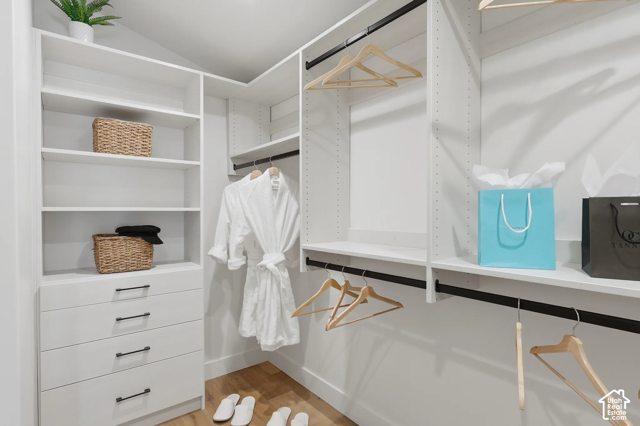 Custom-designed closet system featuring white shelving, multiple hanging rods, and integrated drawer storage with matte black hardware