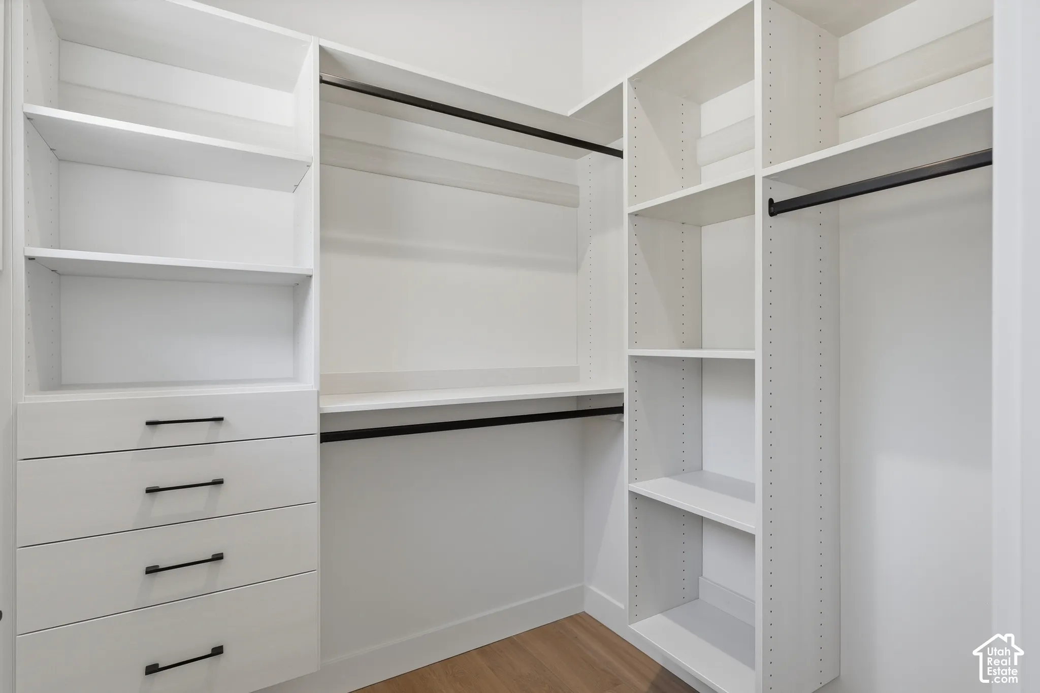 Custom closet system featuring multiple hanging rods, adjustable shelving, and integrated drawers with contemporary black hardware