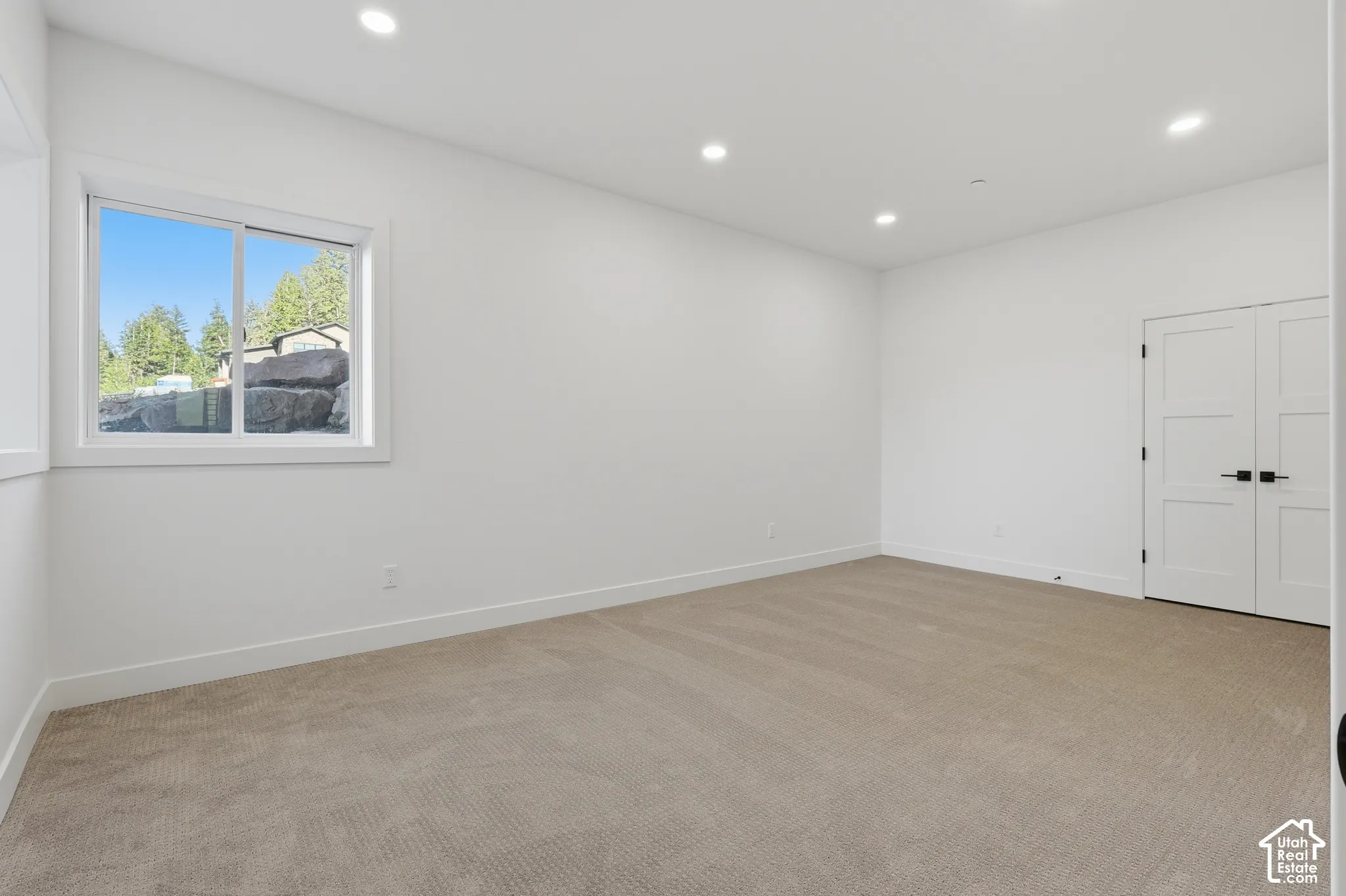 Spacious room featuring neutral carpeting, recessed lighting, and a white-framed window
