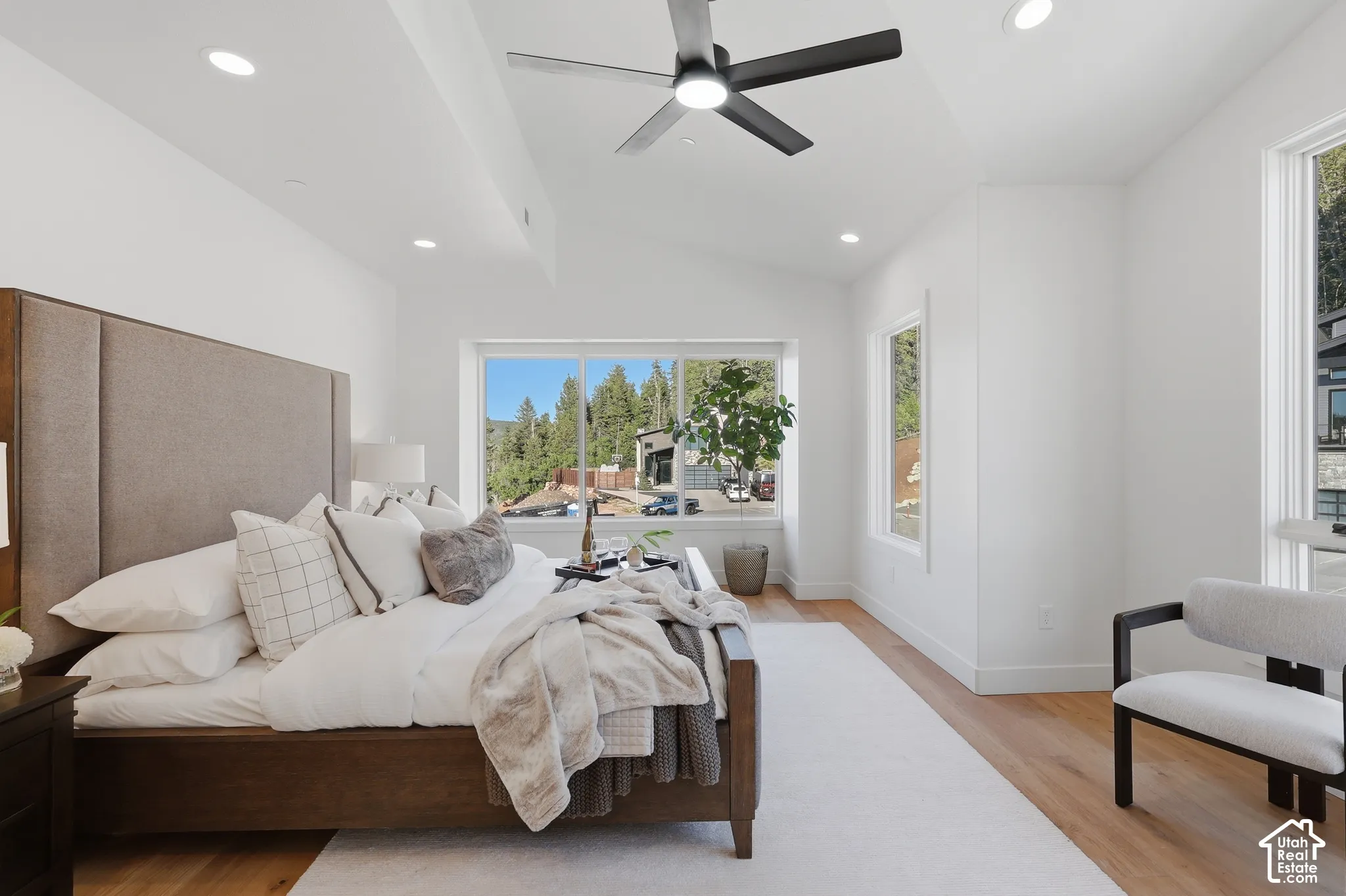Spacious room featuring vaulted ceilings, recessed lighting, wood-finish flooring, and multiple large windows