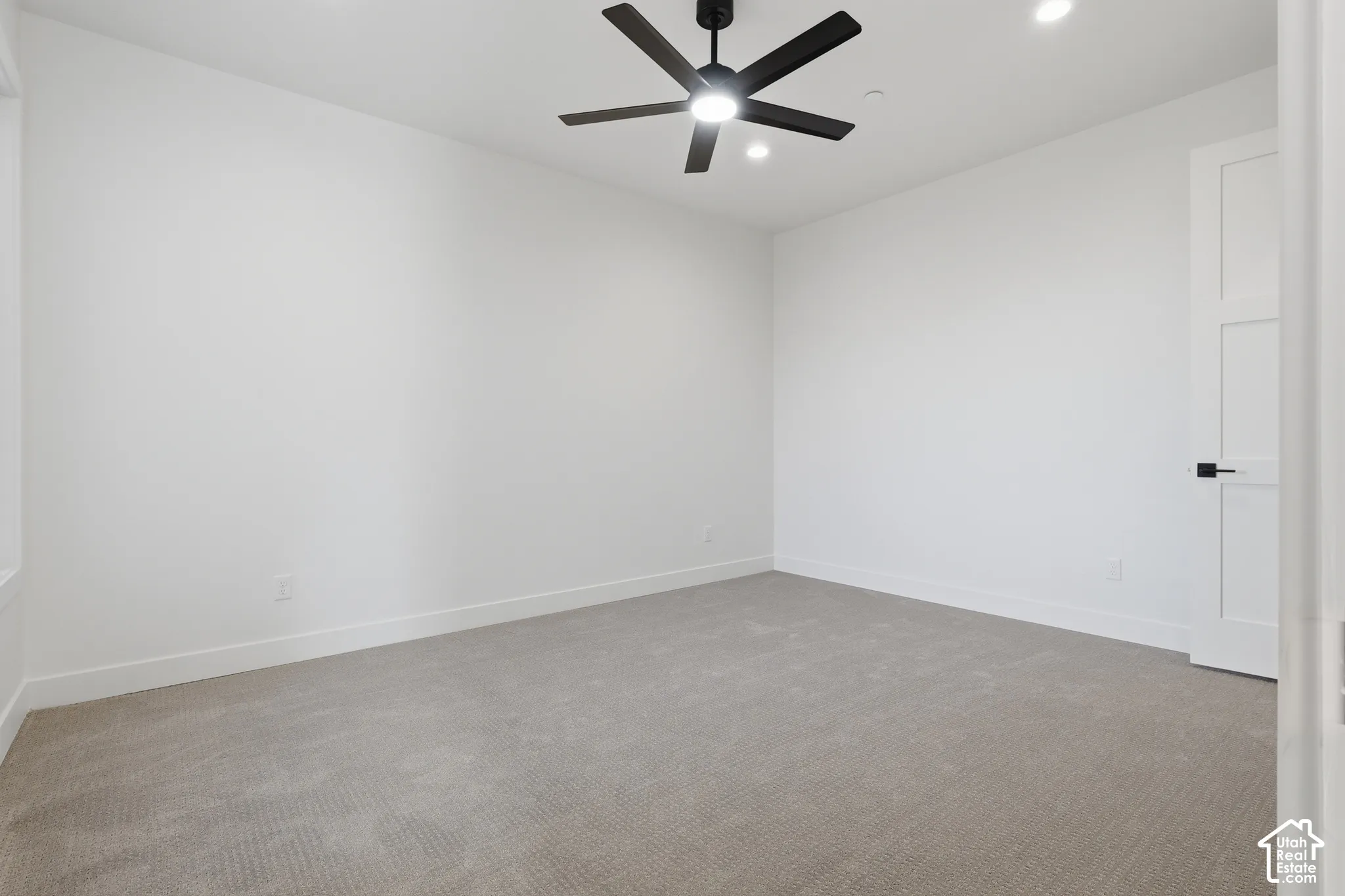 Carpeted room featuring a ceiling fan with integrated lighting, recessed lighting, white walls, and a modern interior door with black hardware