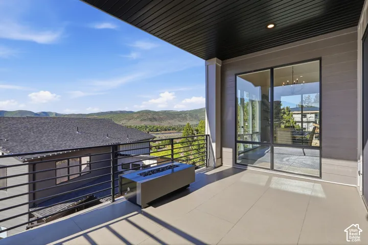Expansive balcony featuring a linear fire pit, tile flooring, and a black metal railing
