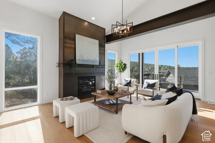 Vaulted ceiling living area featuring a prominent dark-toned fireplace surround, light wood-finish flooring, and large sliding glass doors opening to outdoor space