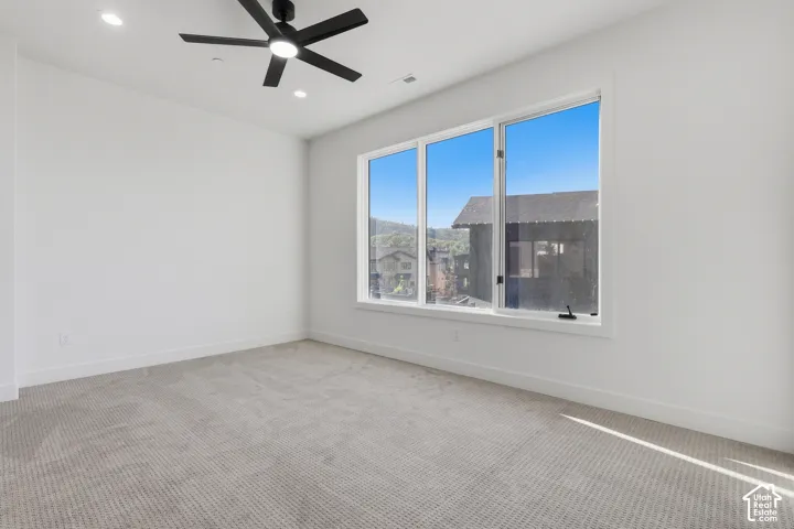 Bright room featuring a large window with multiple panes, recessed lighting, and a ceiling fan