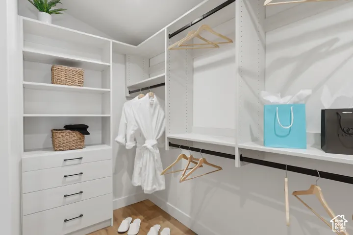 Custom-designed closet system featuring white shelving, multiple hanging rods, and integrated drawer storage with matte black hardware