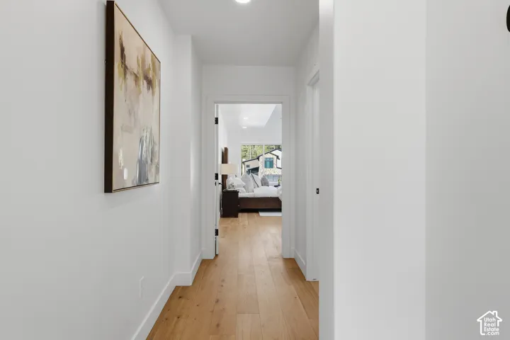 Hallway featuring light wood-finish flooring, white baseboards, and recessed lighting