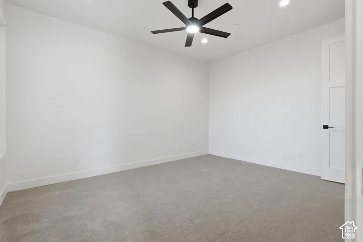 Carpeted room featuring a ceiling fan with integrated lighting, recessed lighting, white walls, and a modern interior door with black hardware
