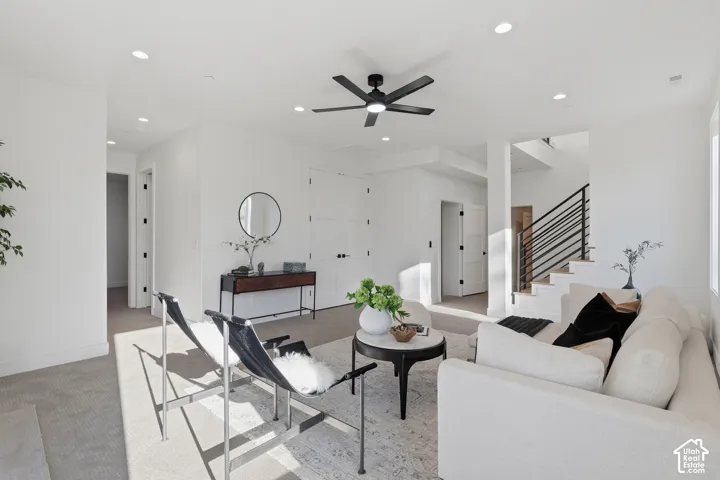 Contemporary living area with recessed lighting, a modern ceiling fan, and light-toned carpeting