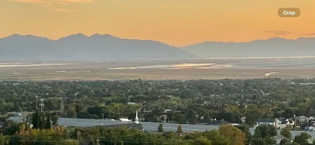 Expansive horizon featuring distant mountains, a broad body of water, and a sprawling community with abundant trees