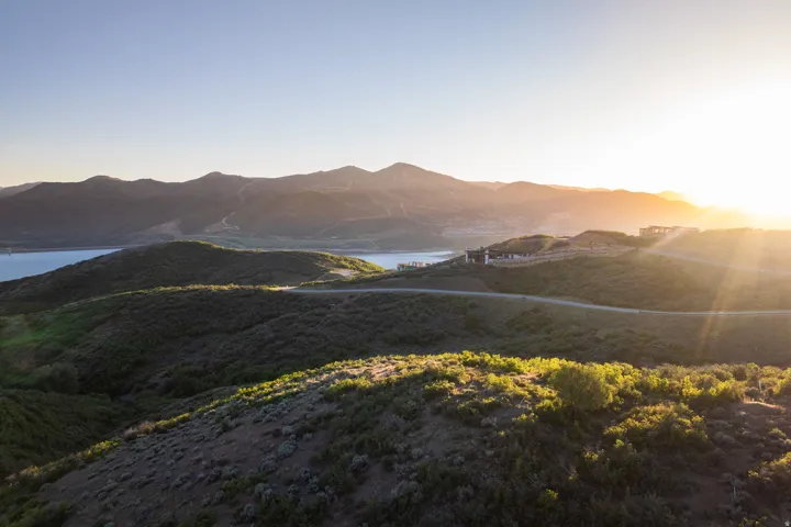Expansive hillside lot featuring a distant water body, mountain backdrop, and natural landscaping