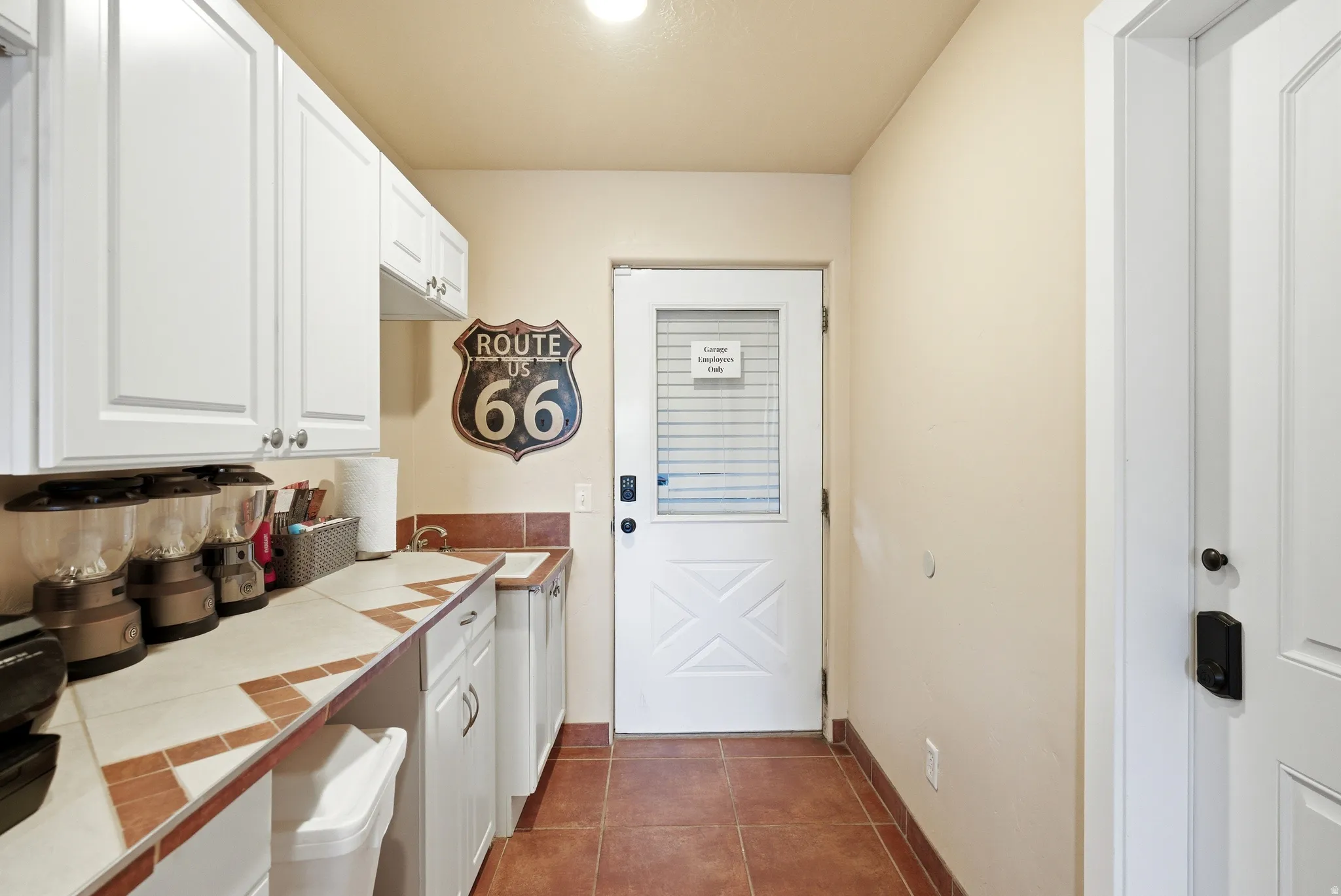 Utility space featuring white cabinetry, tile countertops with a decorative border, and durable tile flooring