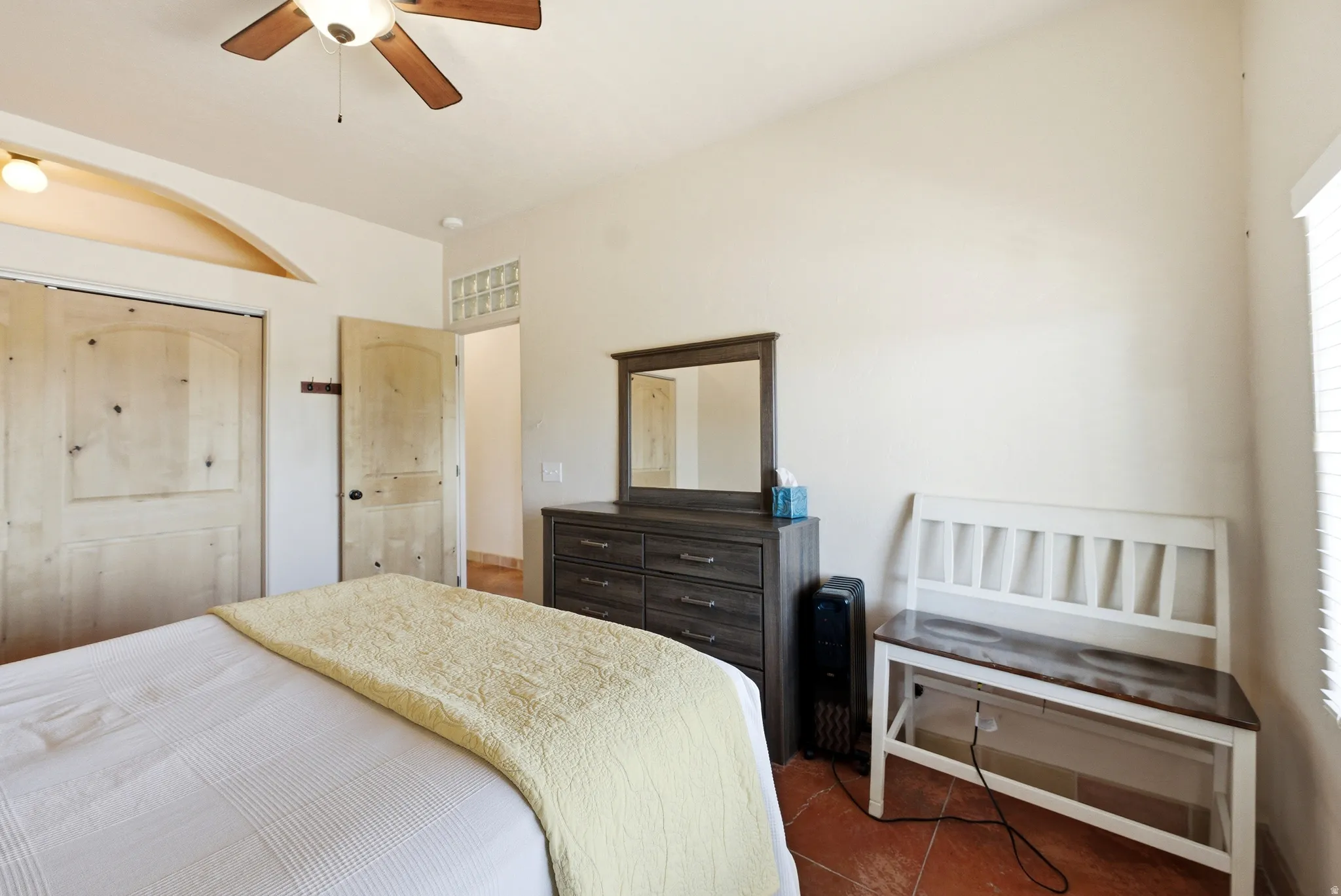 Bedroom featuring wood-finish panel doors, a ceiling fan with integrated lighting, and terra cotta-style flooring