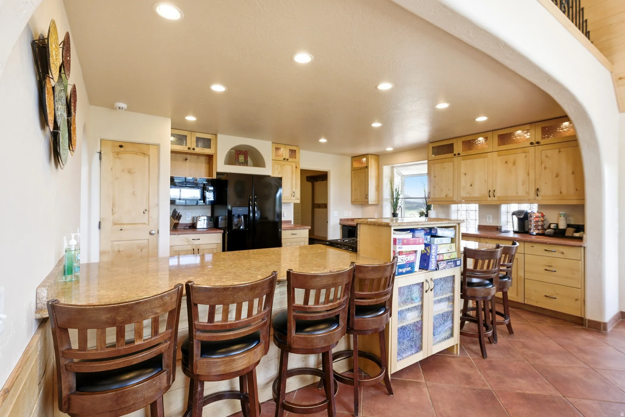 Spacious kitchen featuring an extended island with a breakfast bar, recessed lighting, wood cabinetry, and a full suite of appliances