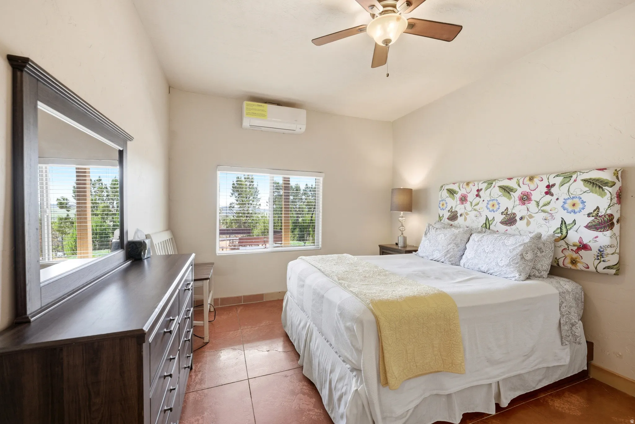 Bedroom featuring terra cotta style flooring, a window with blinds, and a built-in air conditioning unit