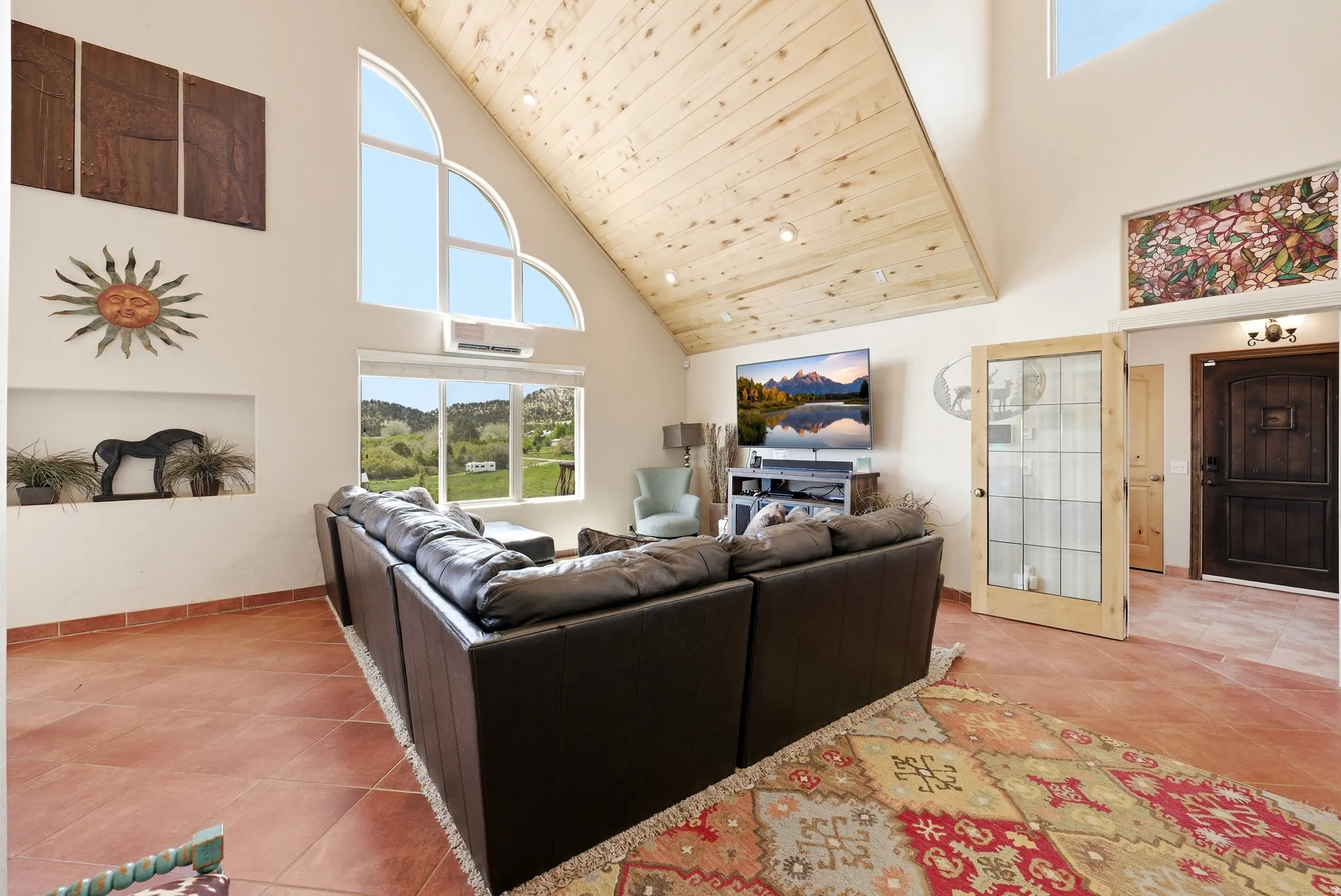 Vaulted wood-paneled ceiling, large arched window, multiple recessed lighting fixtures, built-in wall niche, and tile flooring