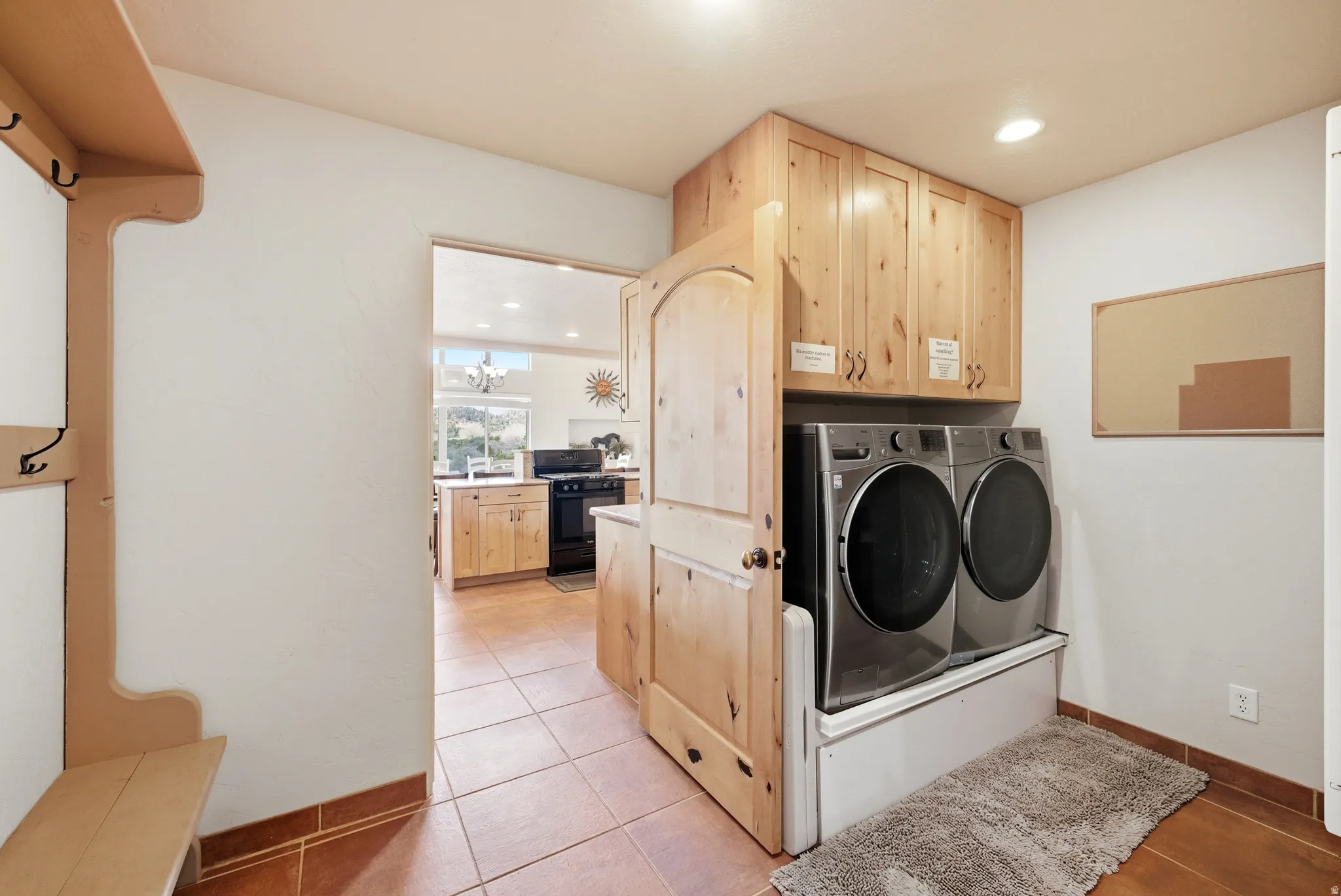 Laundry area featuring stacked front-load machines, wood-finish cabinetry, and recessed lighting