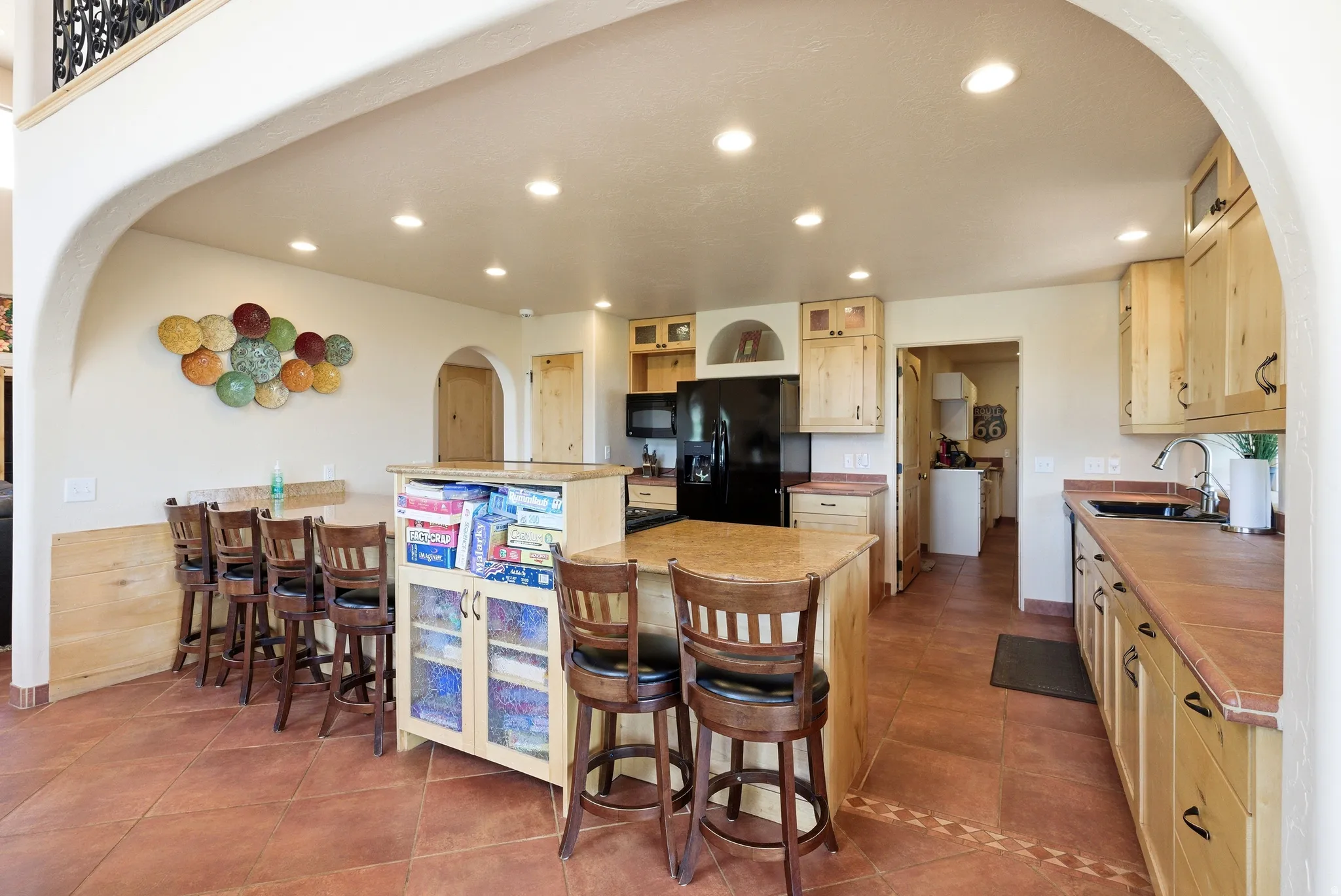 Kitchen featuring light wood cabinetry, a central island, recessed lighting, black appliances, and terracotta-toned floor tile