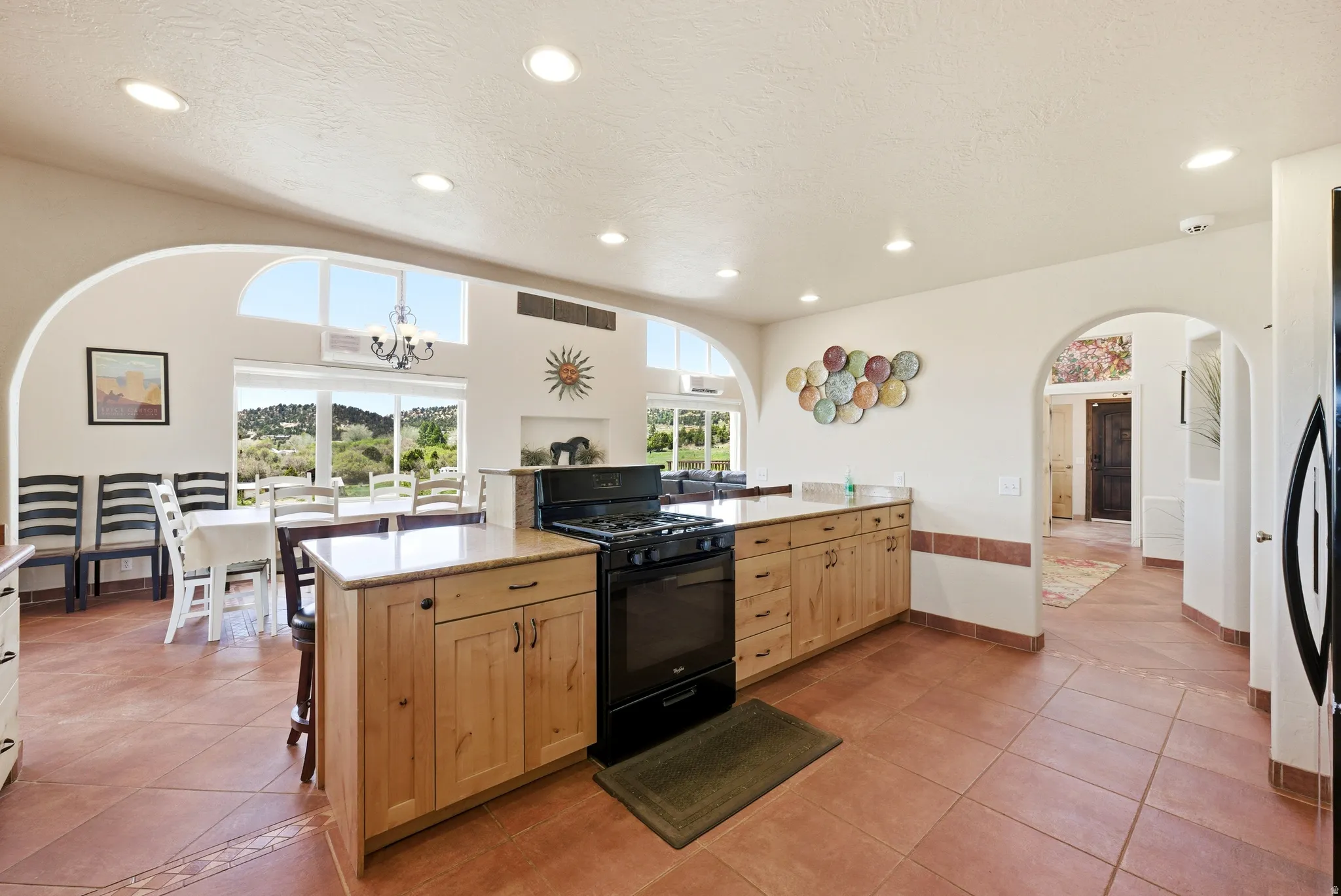 Kitchen featuring extensive wood cabinetry, a black range with an overhead microwave, and a peninsula with a light-toned countertop