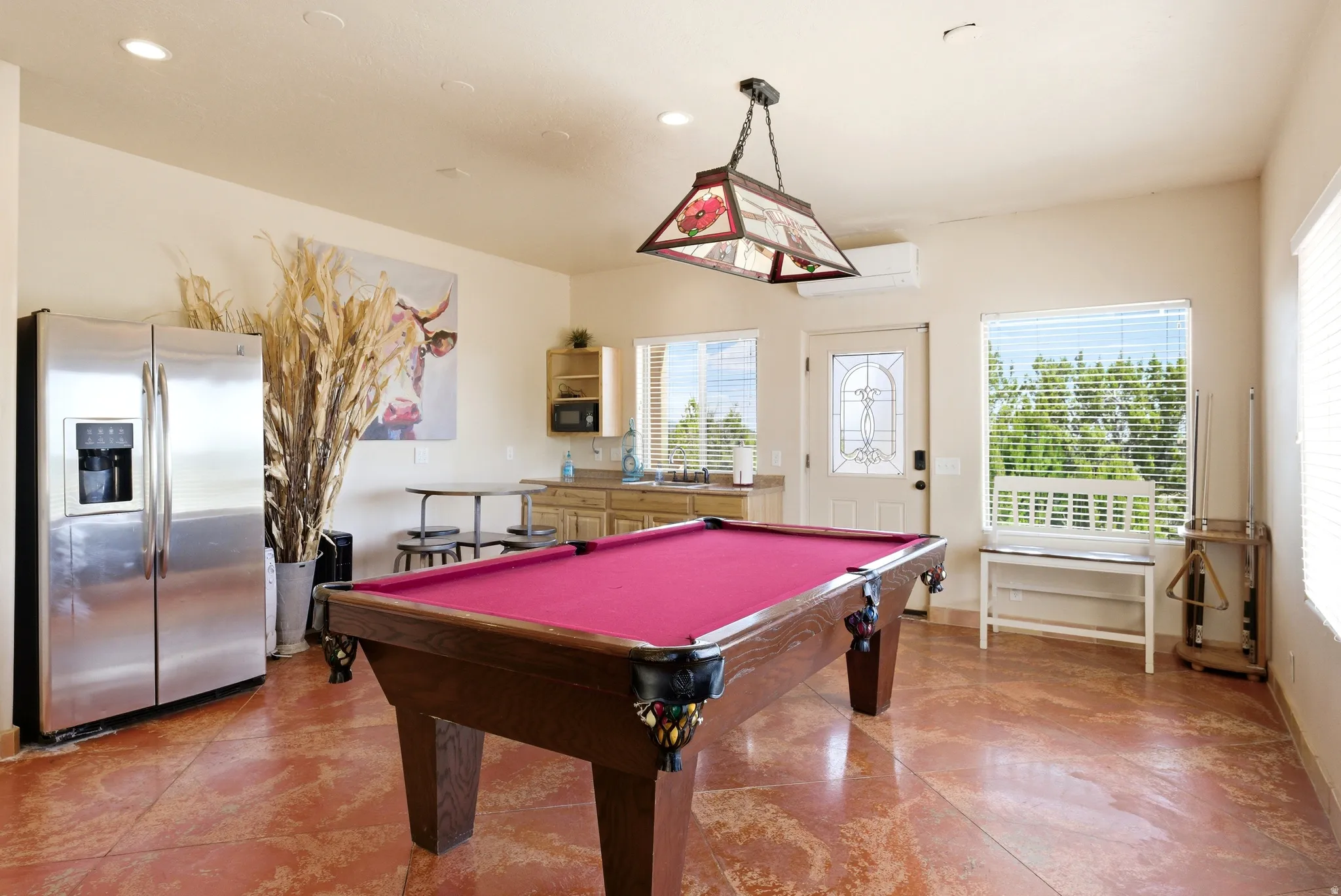 Recreational space featuring a pool table with crimson felt, a wet bar with a stainless steel sink, and durable reddish-brown flooring